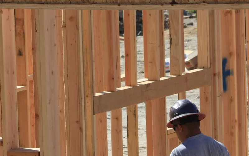 Contractor in a hard hat framing the walls of a new house