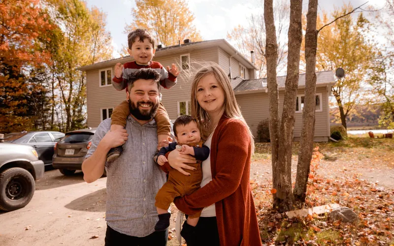 Young parents holding their two children outside on a fall day